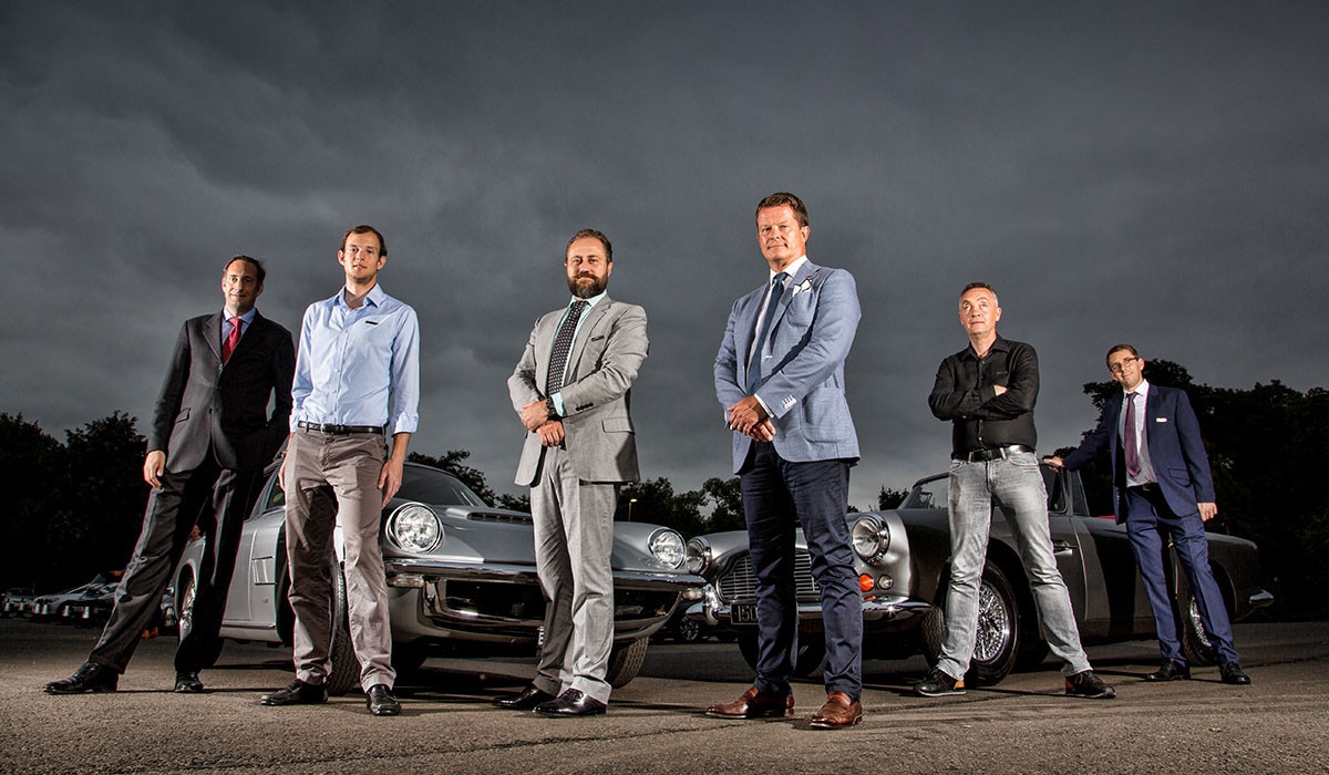 6 men standing in front of cars
